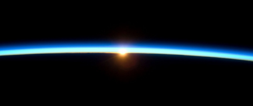 A stock image of the sun peeking over Earth's atmosphere